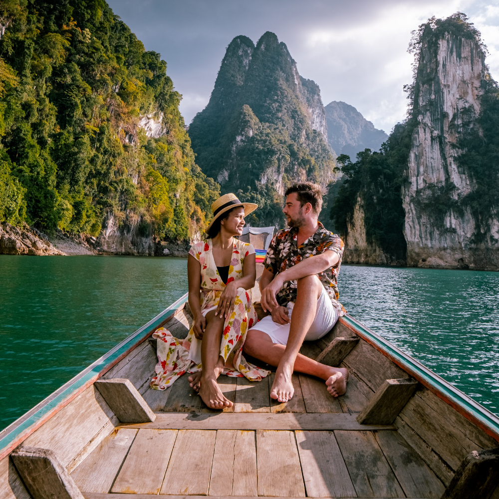 Couple sitting on a boat in a turquoise bay surrounded by tall limestone cliffs
