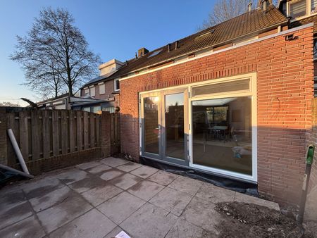 Een bakstenen huis met een terras ervoor