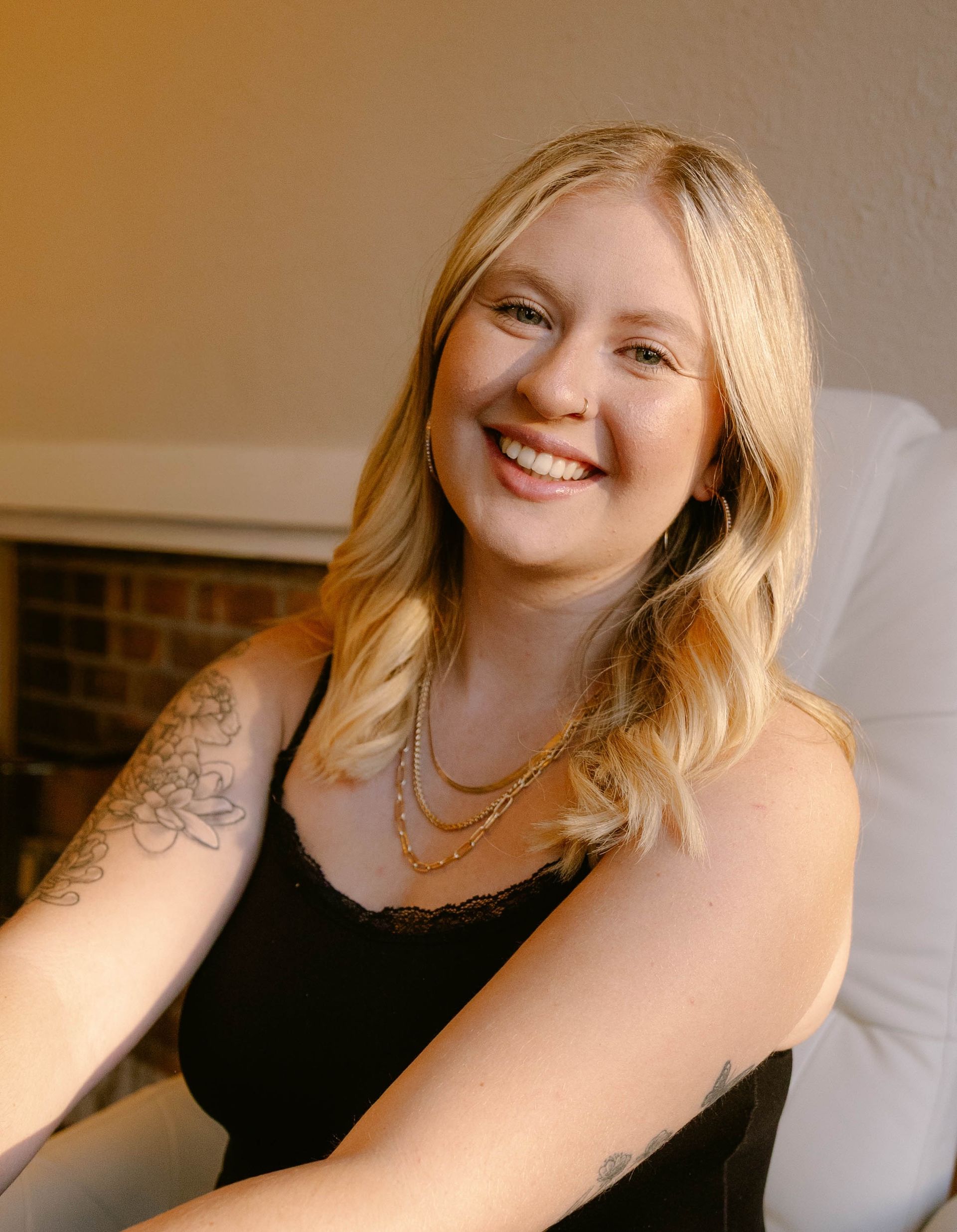 Robin McIntyre — Laramie, Wy — Luna Salon & Spa Smiling woman with long wavy hair in a dark top, posed against a stone wall background