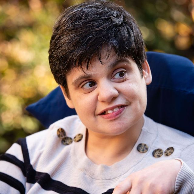 A woman is sitting in a chair and smiling.