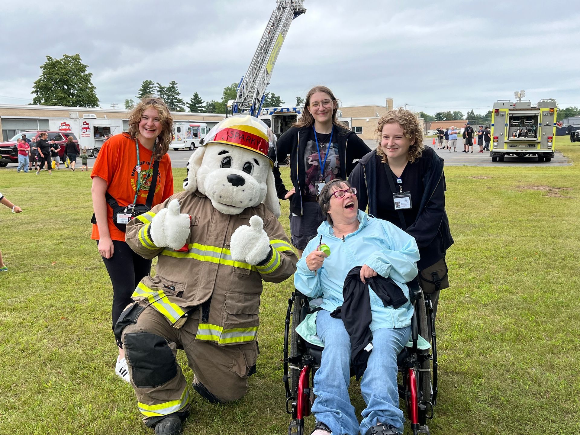 A group of women is posing for a picture with a firefighter mascot.