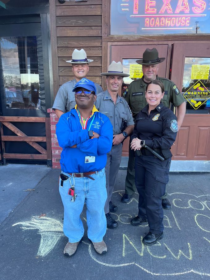 A group of people standing in front of a building that says texas roadhouse.