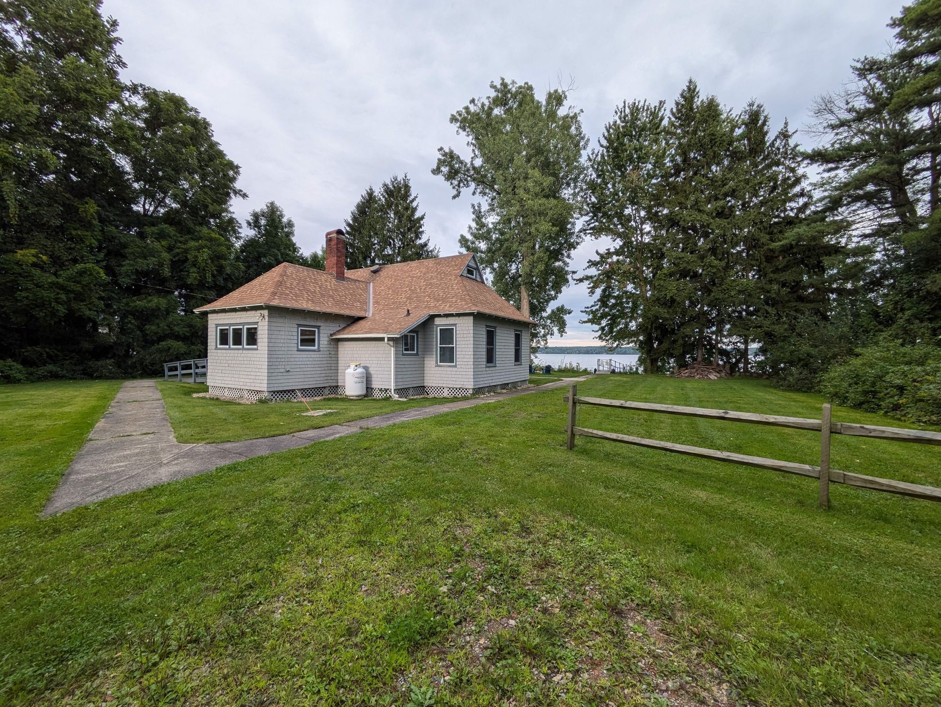 A small white house is sitting in the middle of a lush green lawn.