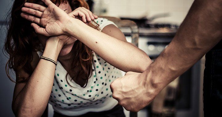 woman cowers in fear in front of clenched fist