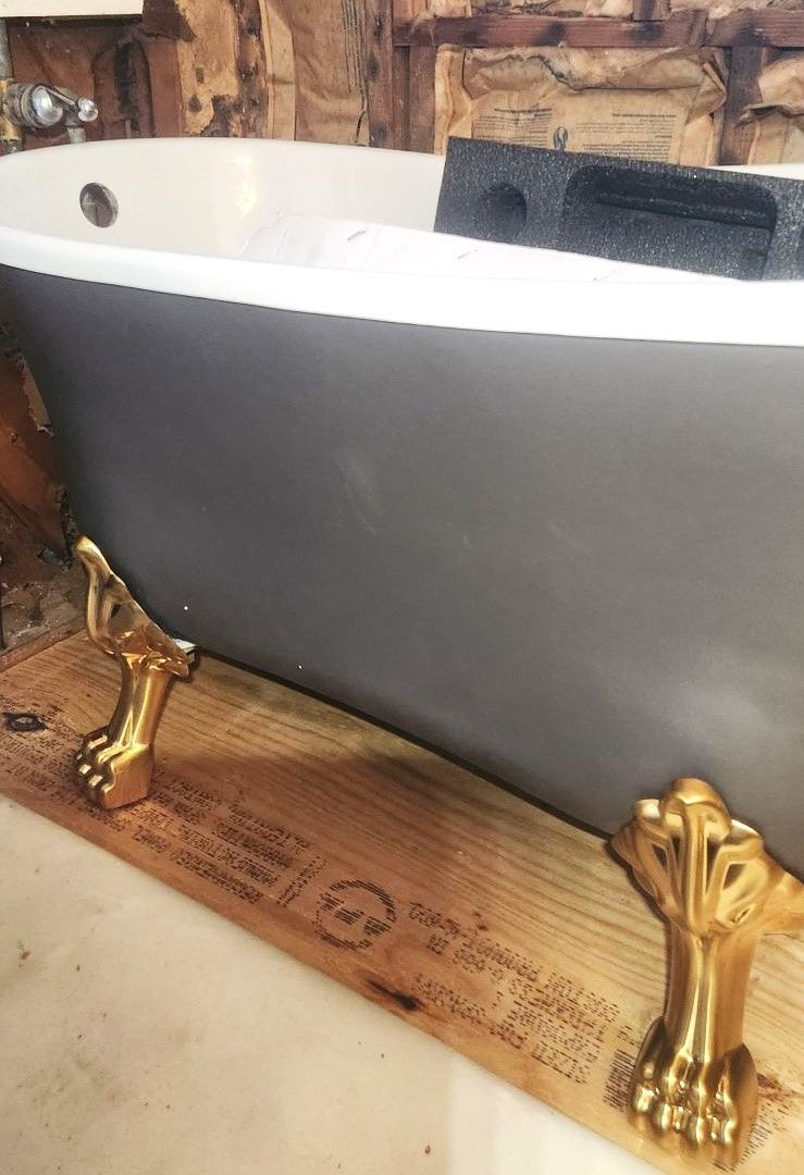 A Bathtub with Gold Feet Is Sitting on A Wooden Table.