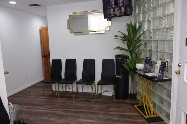 Waiting room with black chairs, gold accents, and a glass block wall.