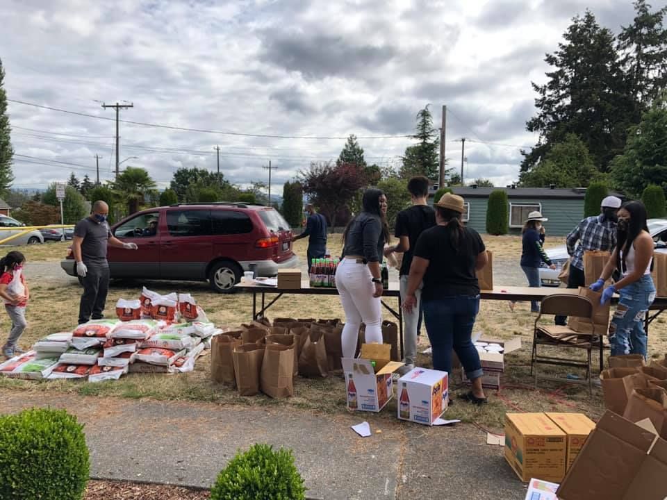 A group of people are standing around a table in a parking lot.