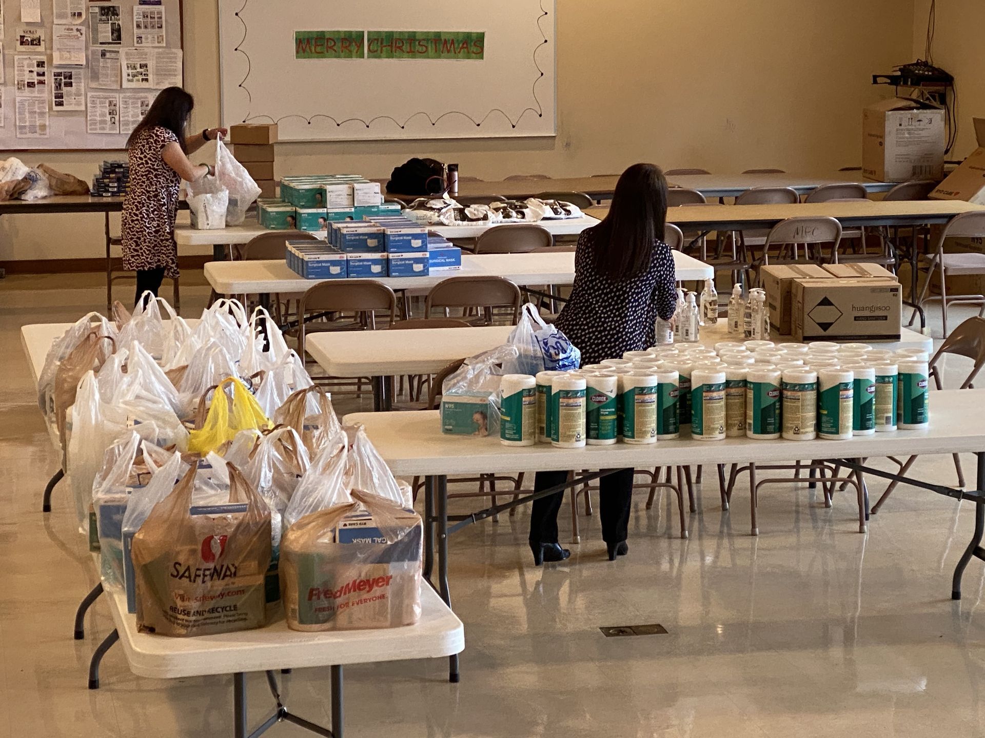 A woman is standing in a room filled with tables and bags of food.