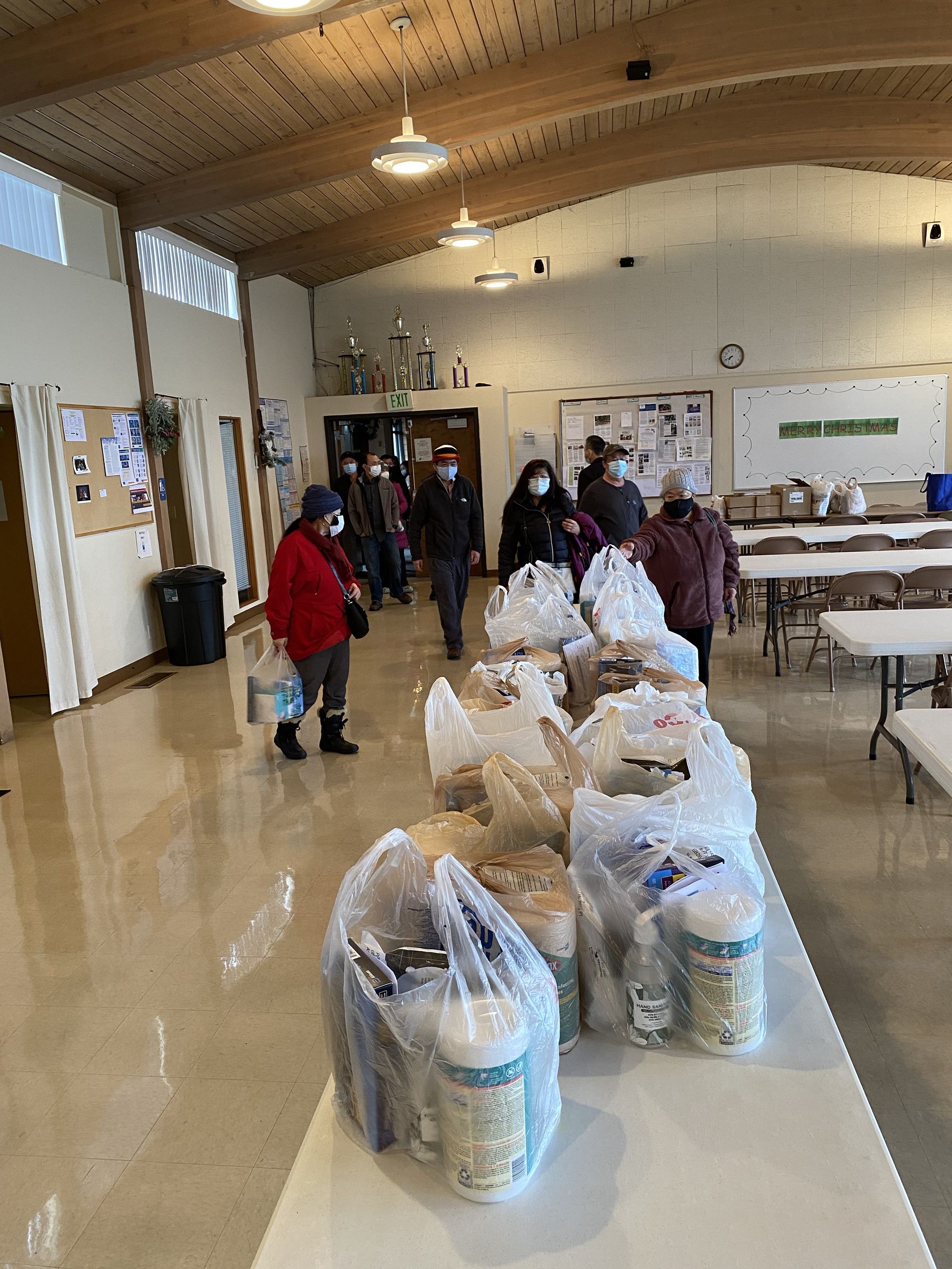 A group of people are standing around a table filled with bags of food.