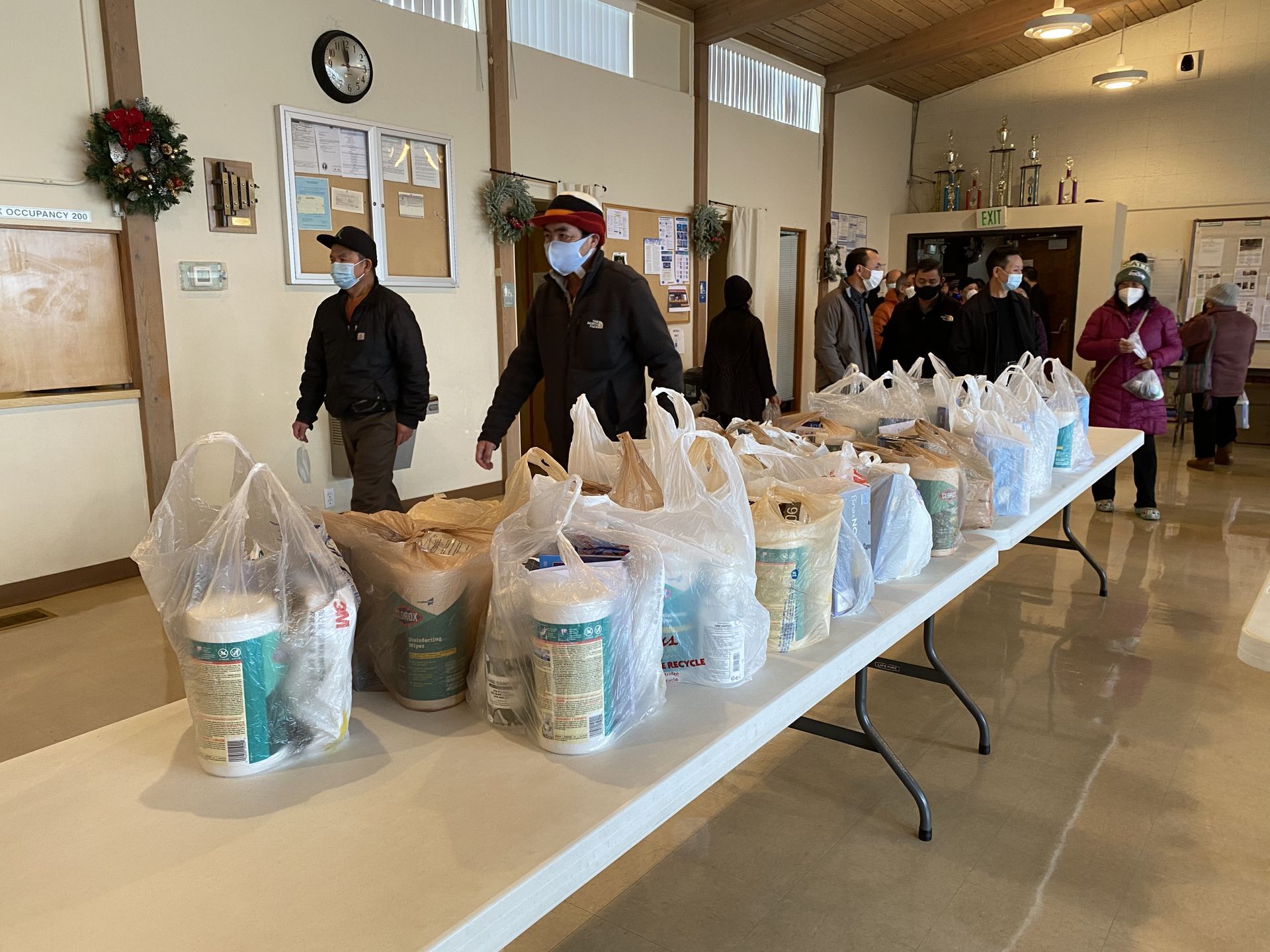 A group of people are standing around a table filled with bags of food.