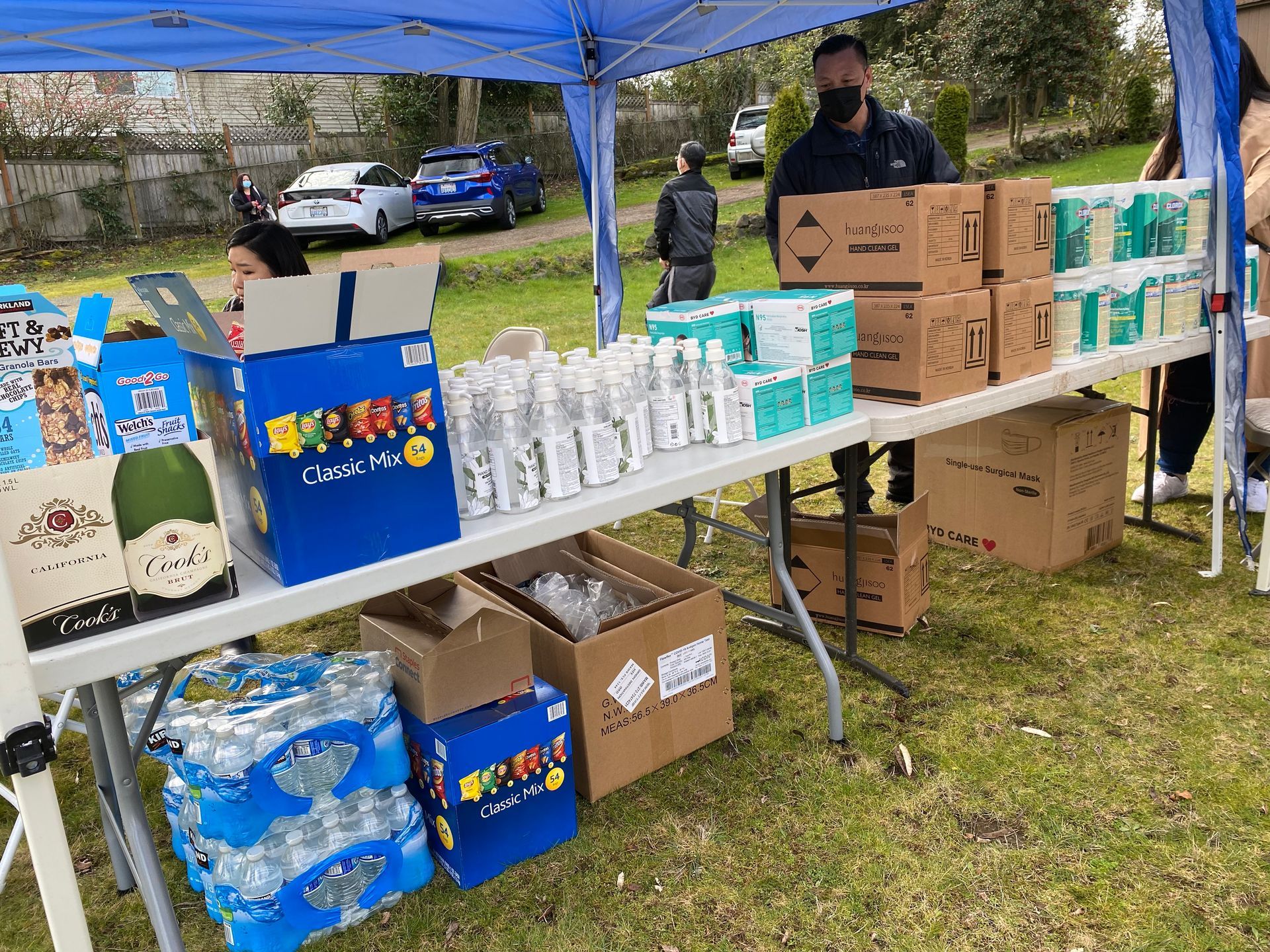 A table filled with boxes and bottles of water under a blue tent.