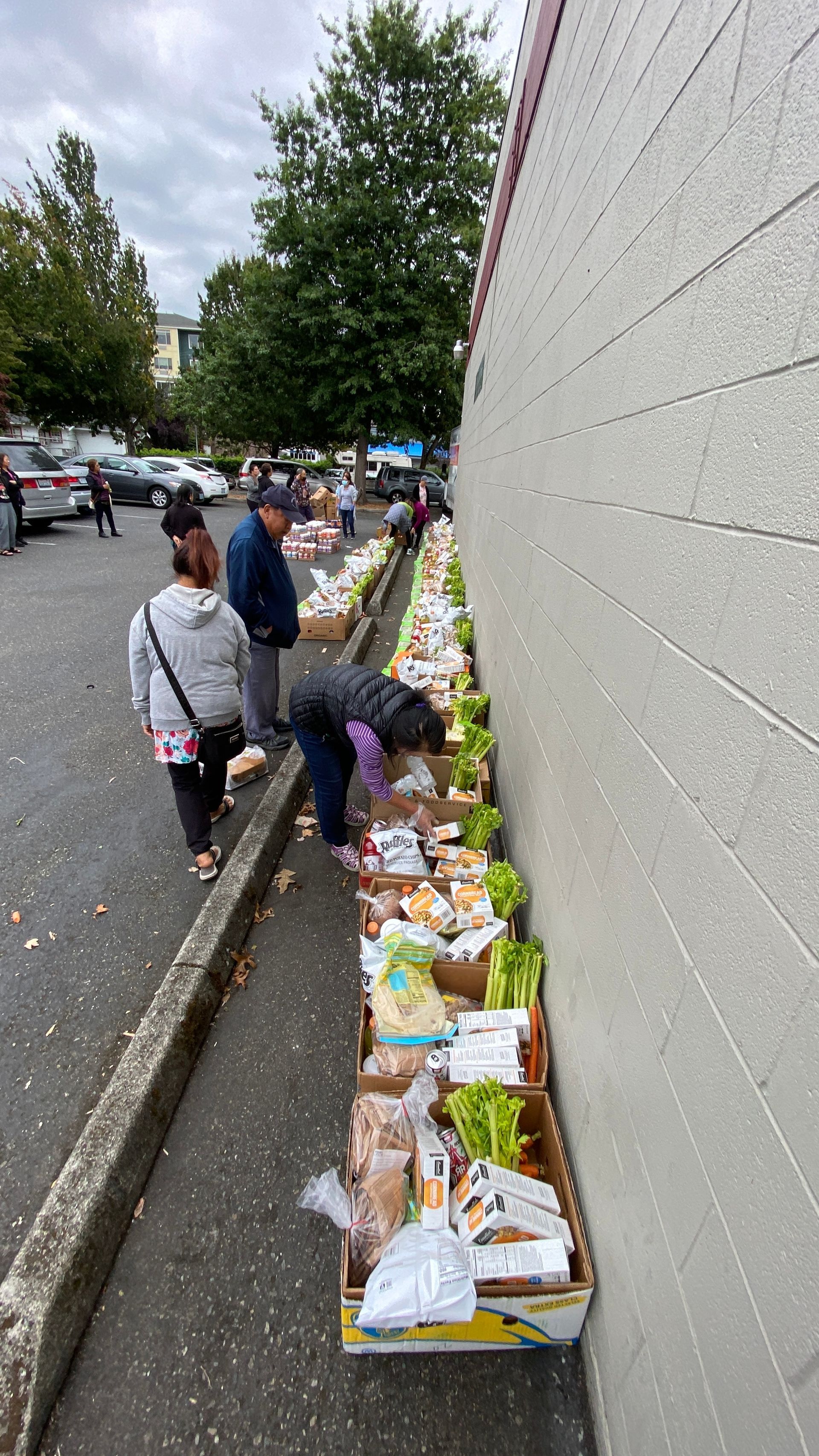 A group of people are standing on a sidewalk next to a wall.