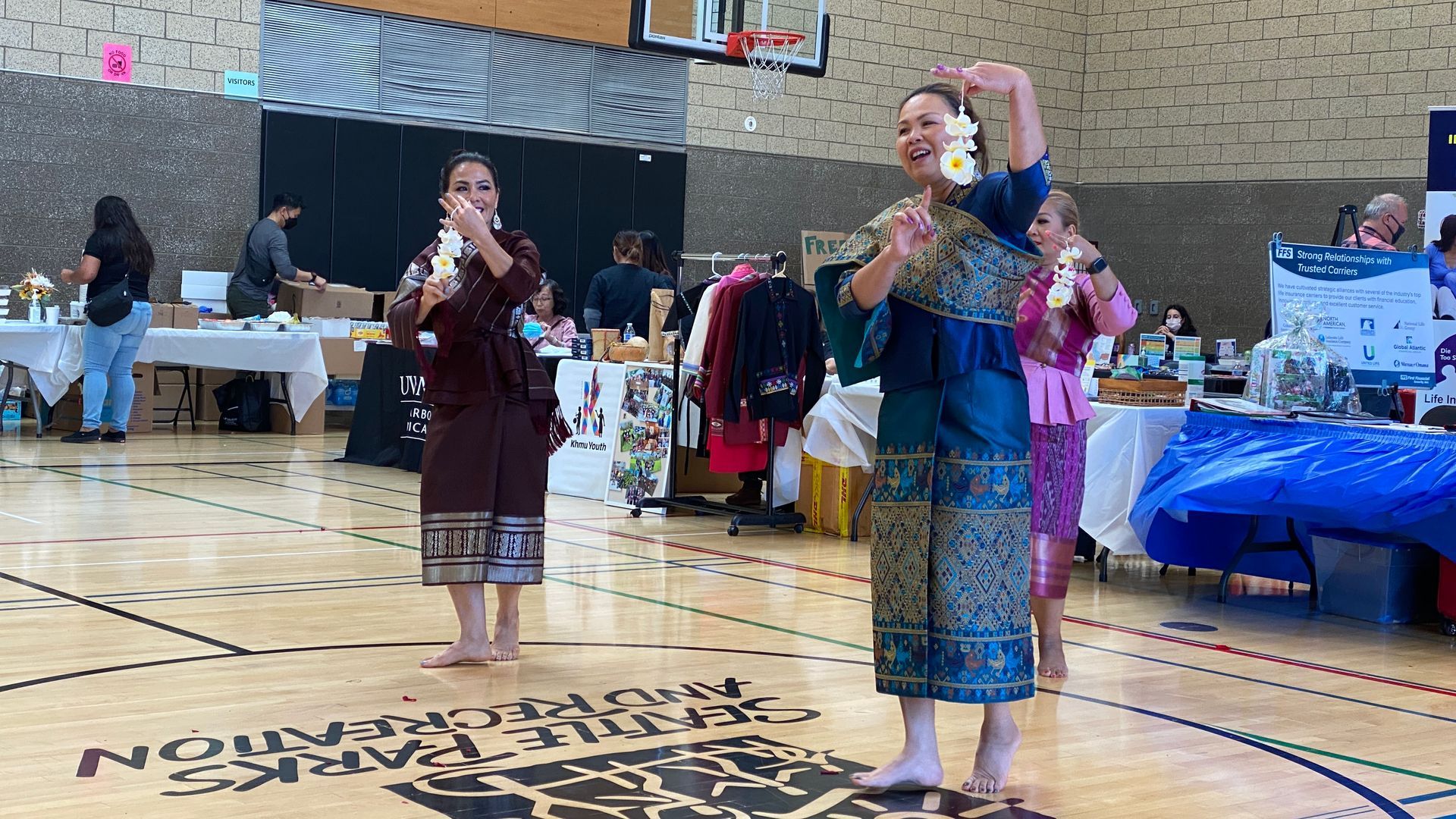 Two women are standing on a basketball court singing into microphones.
