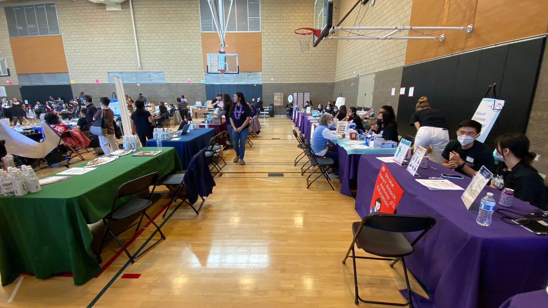 A large group of people are sitting at tables in a gym.