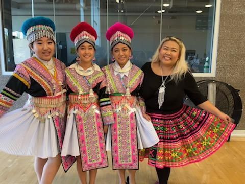 A woman is standing next to three girls in traditional costume