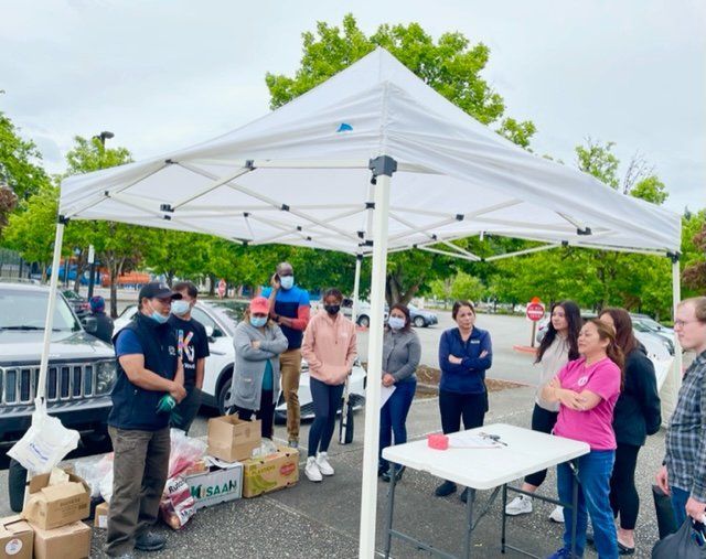A group of people standing under a white tent in a parking lot