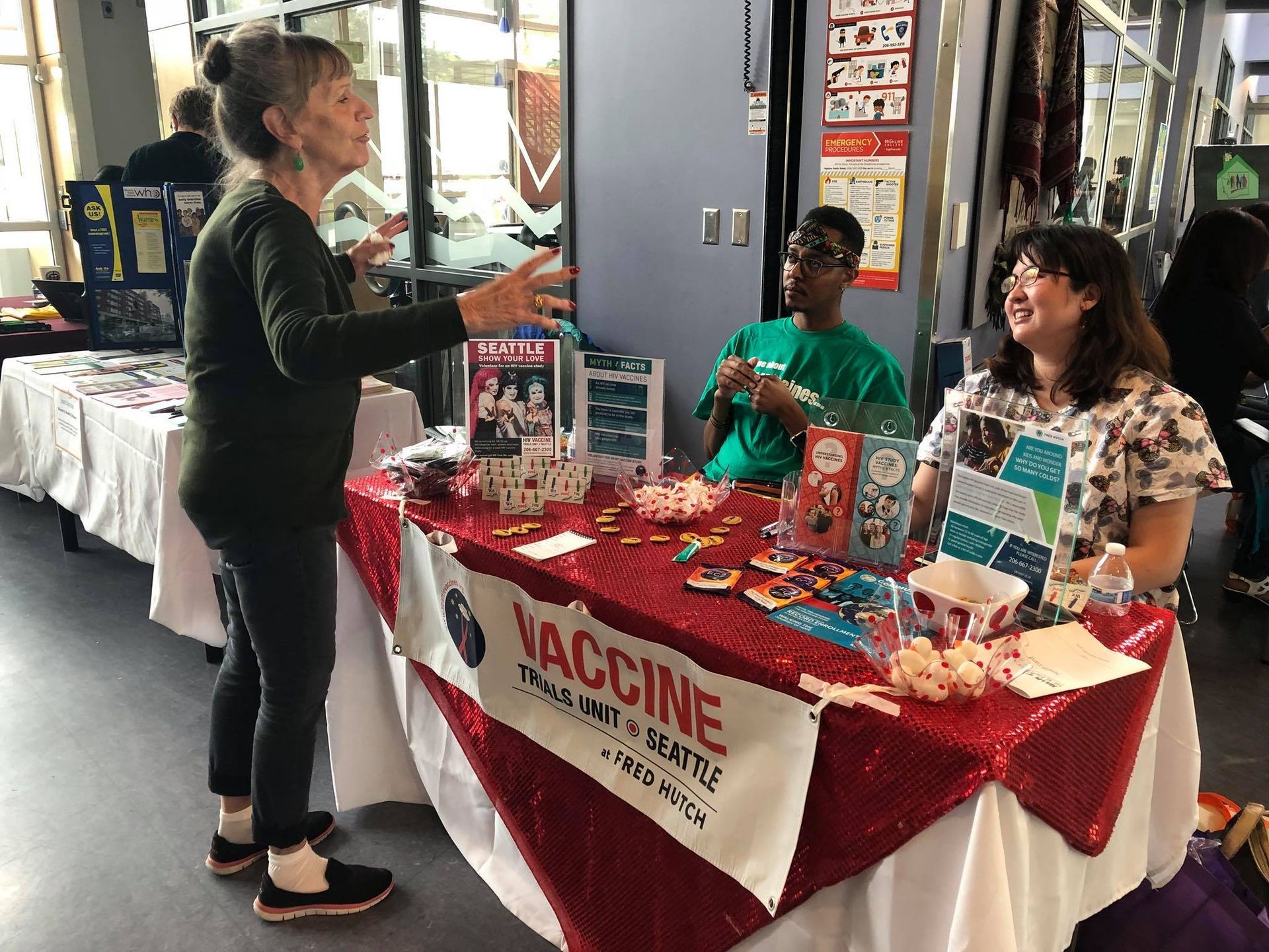 A woman is standing in front of a table with a vaccine sign on it.