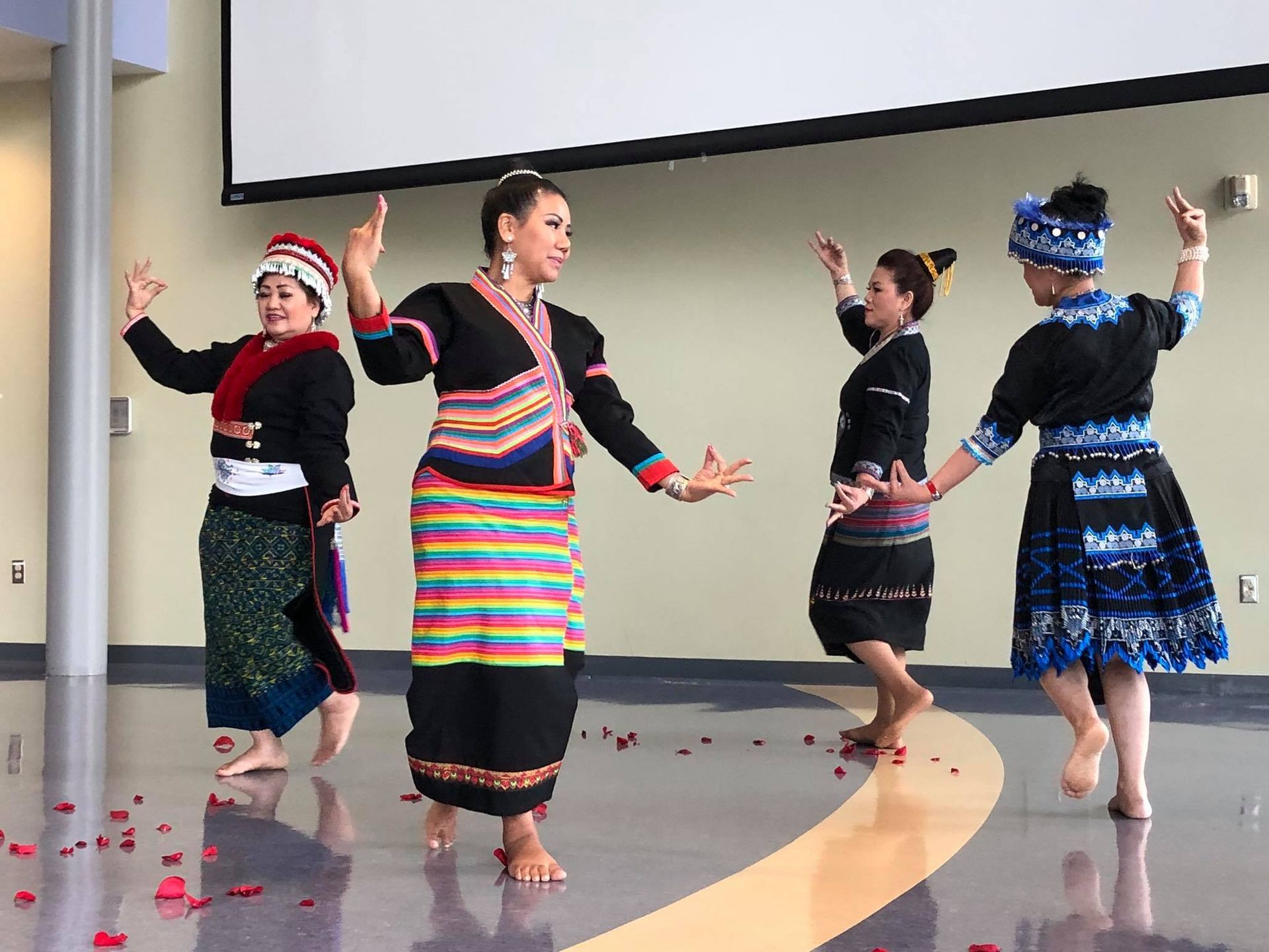 A group of women are dancing in a room with petals on the floor.