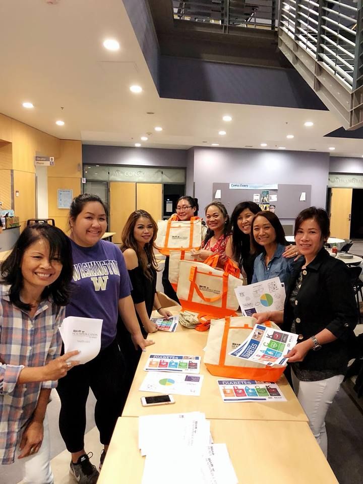 A group of women are standing around a table holding papers and bags.