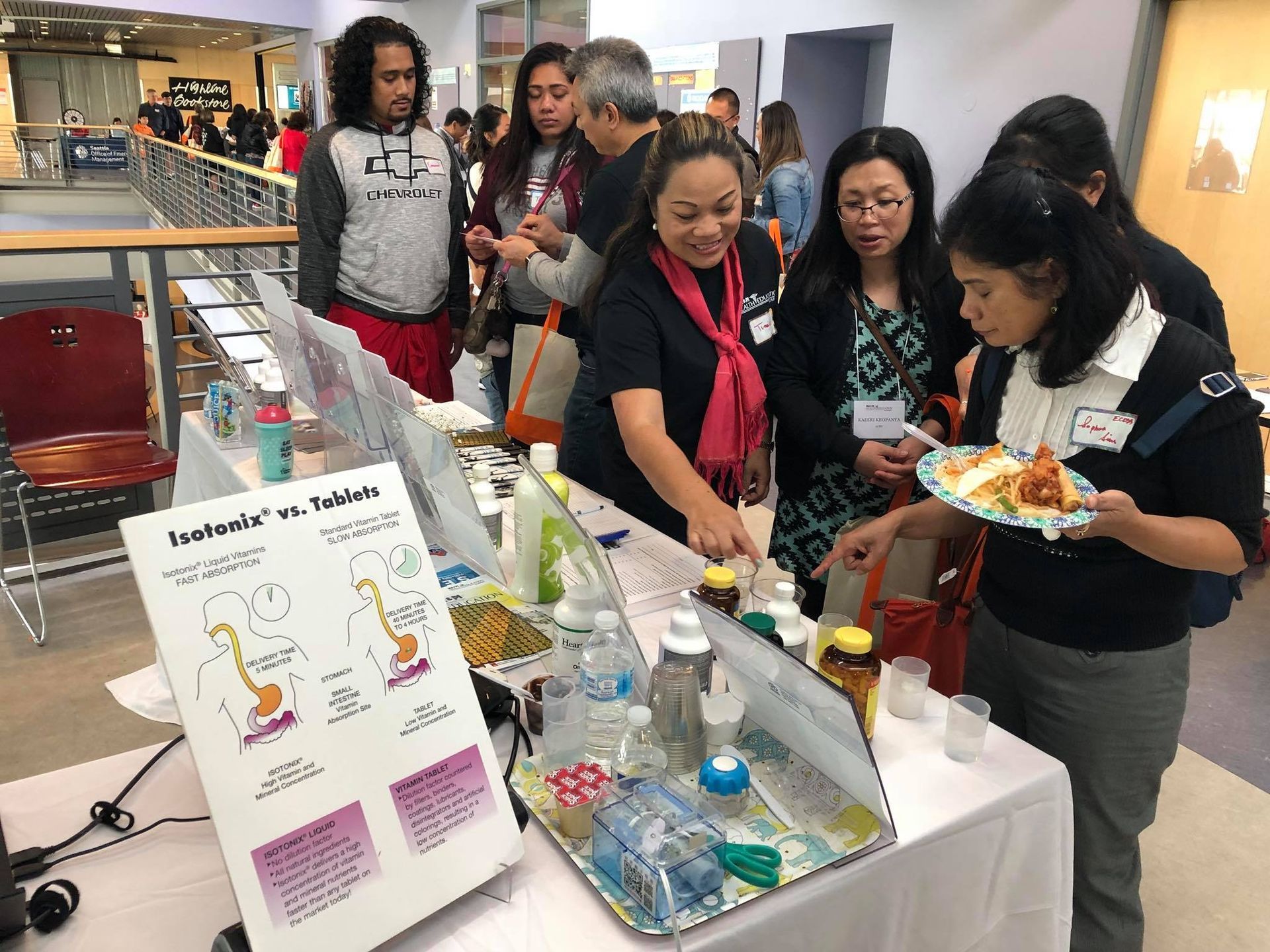 A group of people are standing around a table eating food.
