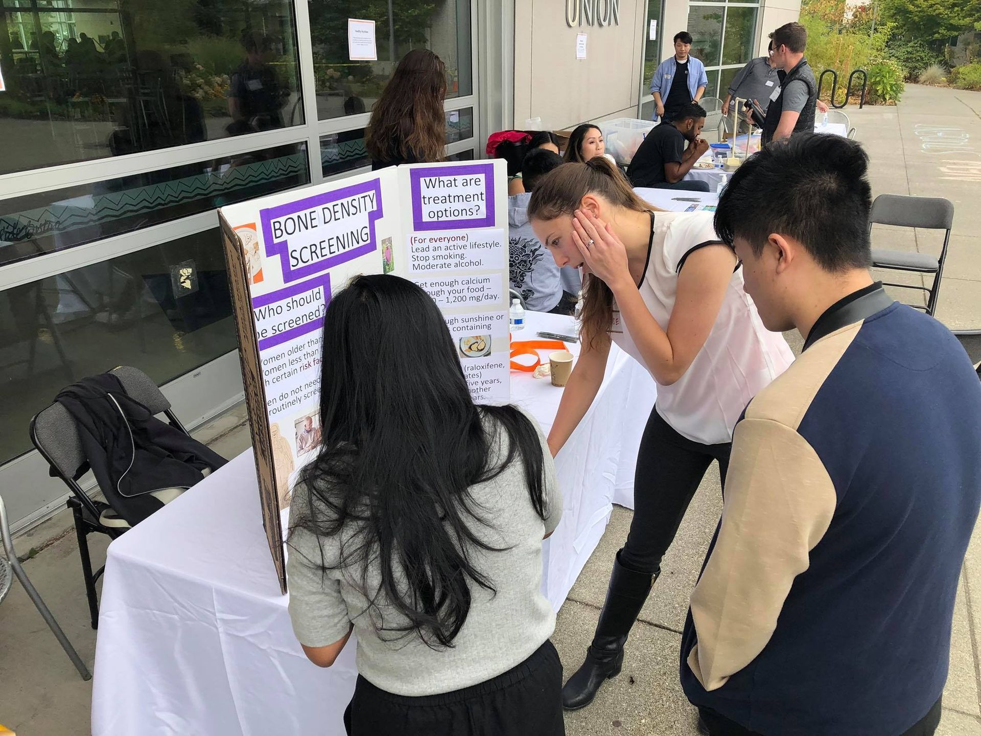 A group of people are standing around a table looking at a poster.