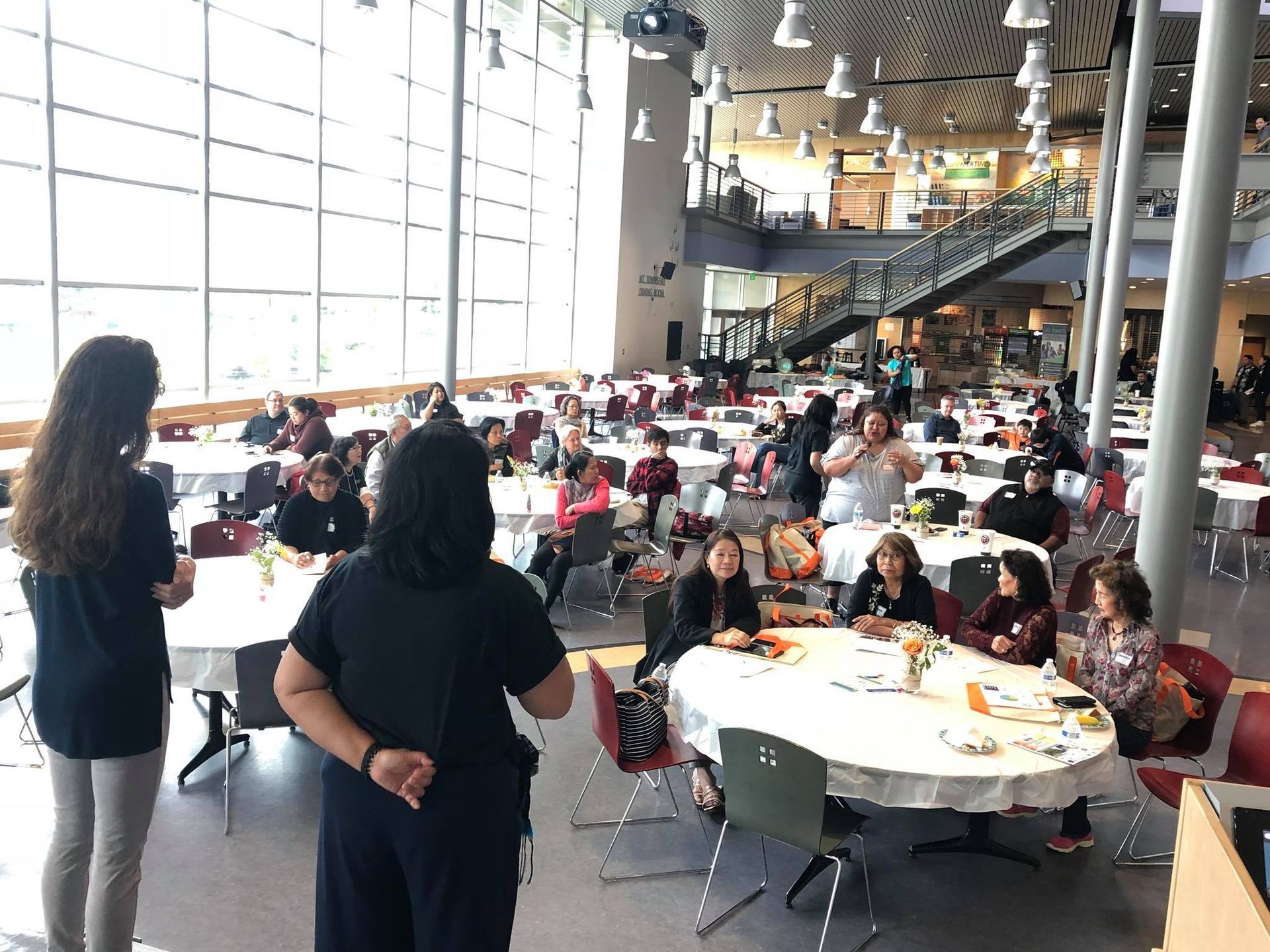 A group of people are sitting at tables in a large room.