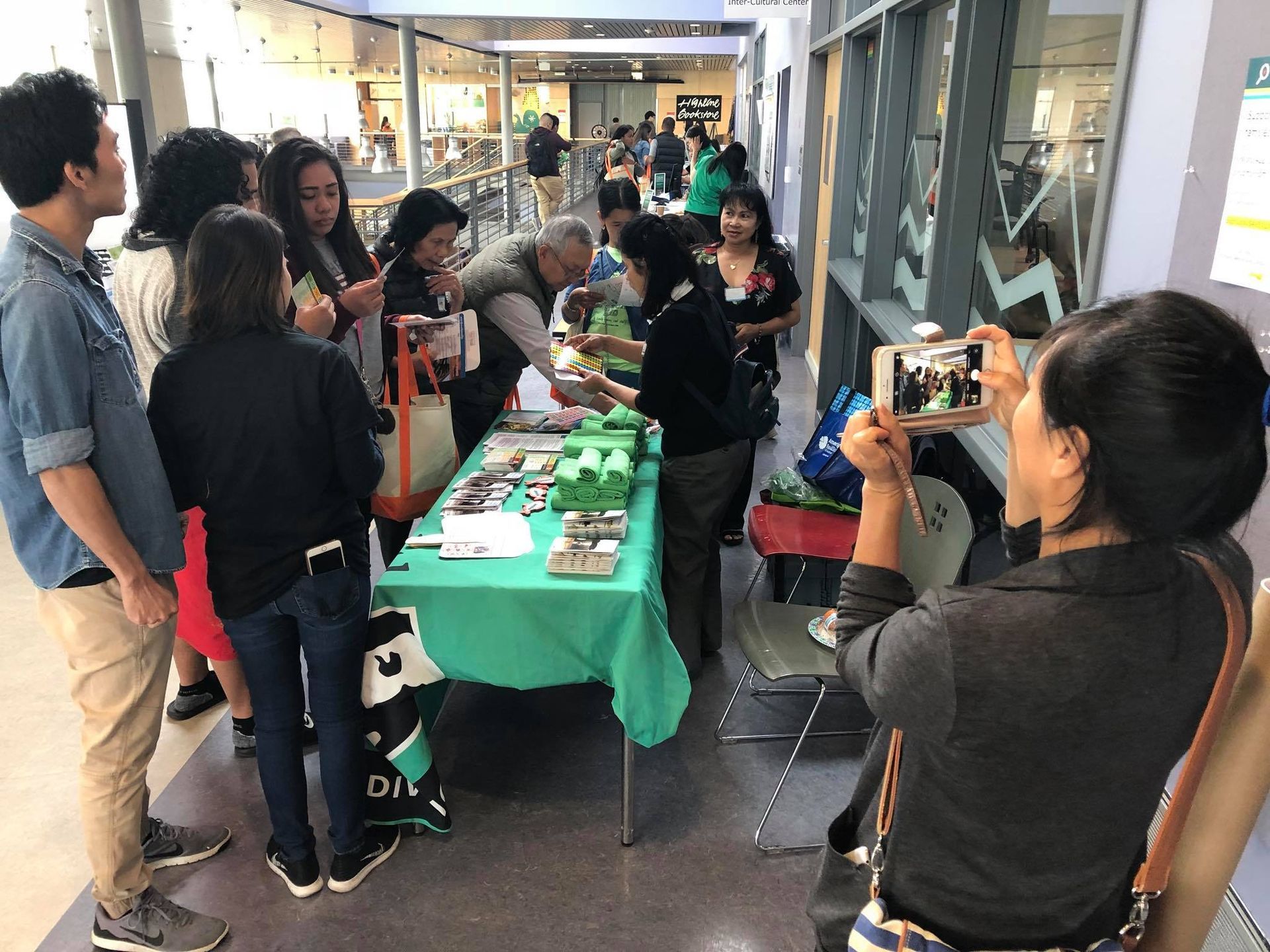 A woman is taking a picture of a group of people standing around a table.