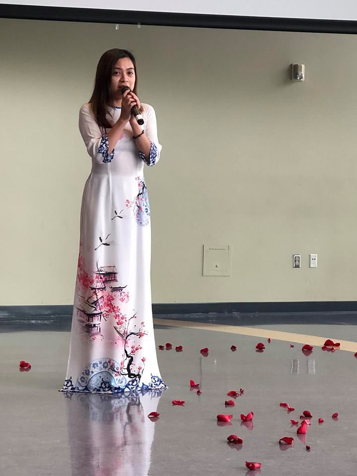 A woman in a long white dress is singing into a microphone