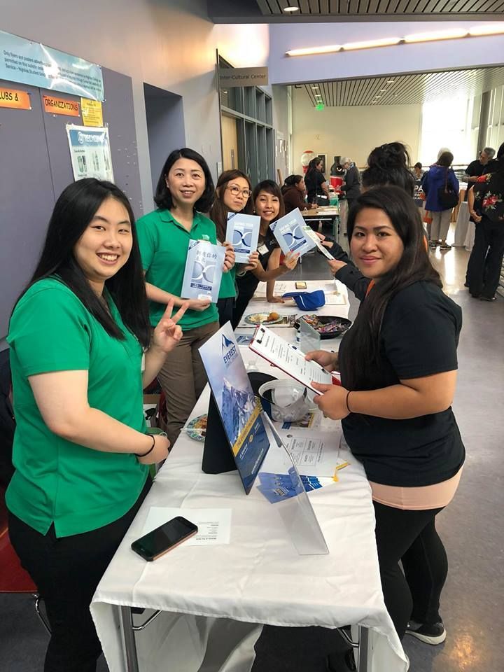 A group of women are standing around a table holding papers.