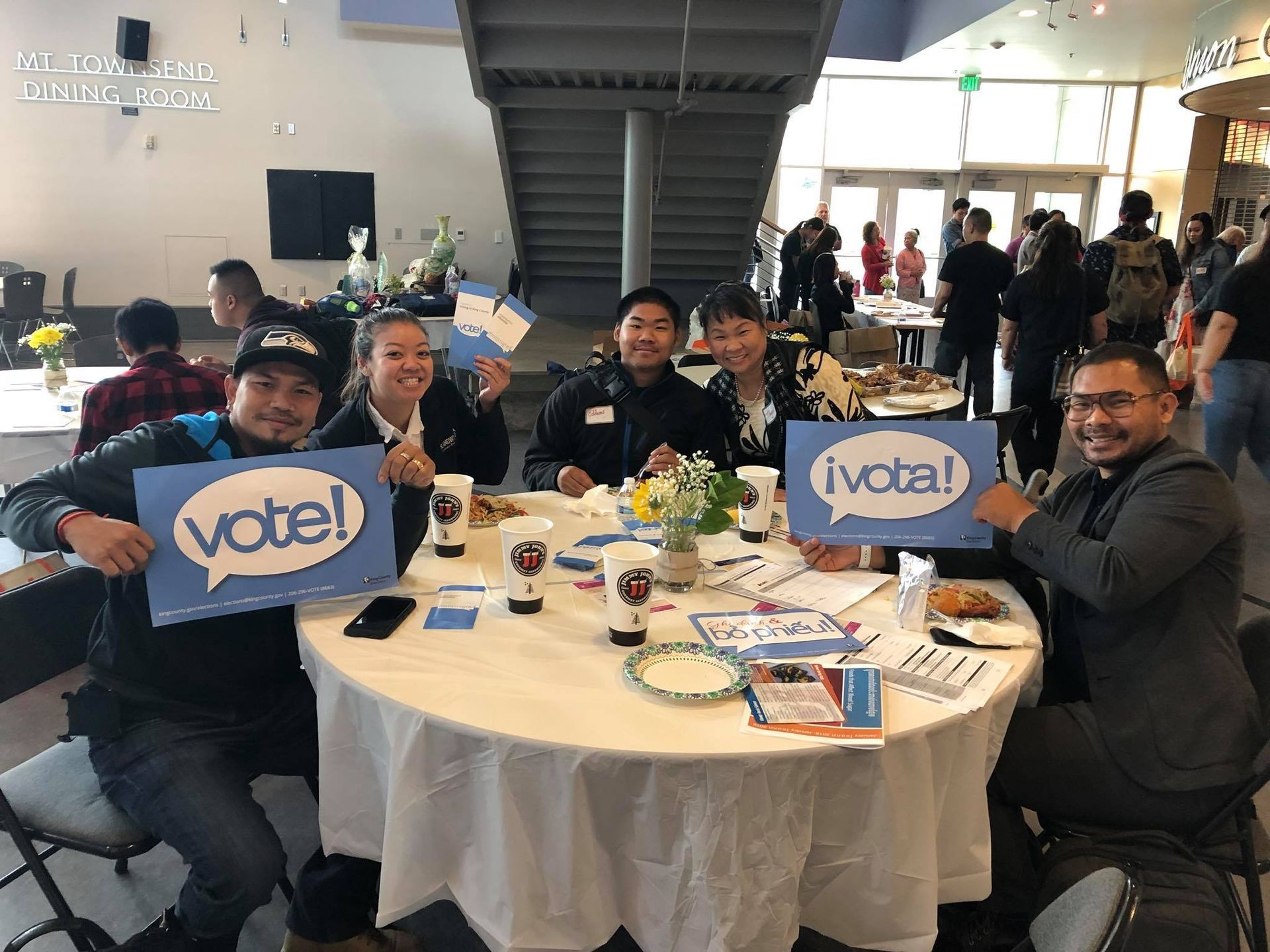 A group of people are sitting at a table holding signs that say vote.