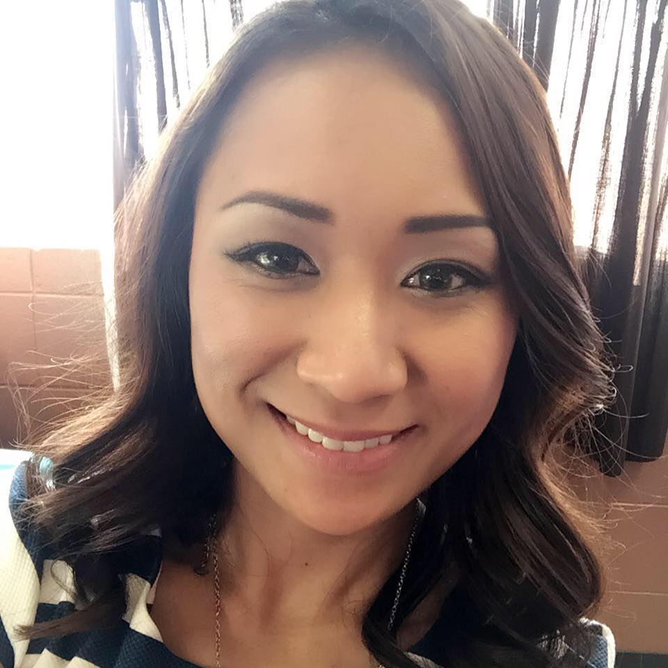 A close up of a woman 's face smiling in front of a window