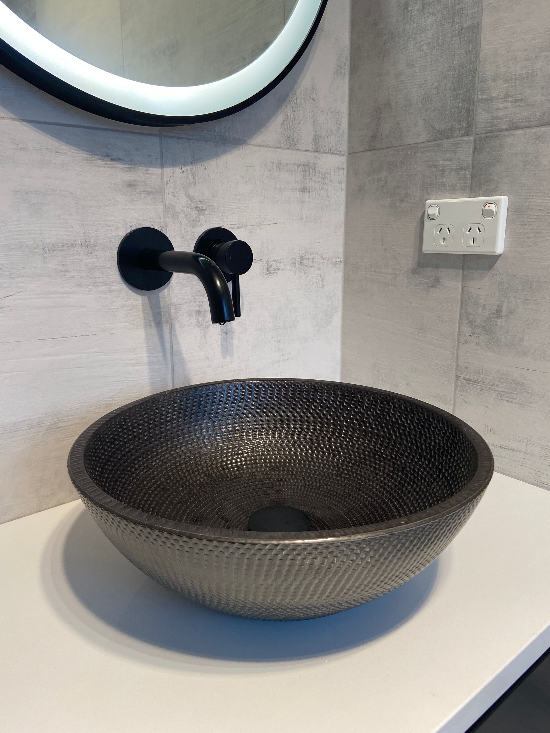 Compact bathroom design with modern sink and black-framed mirror in a small bathroom in Auckland