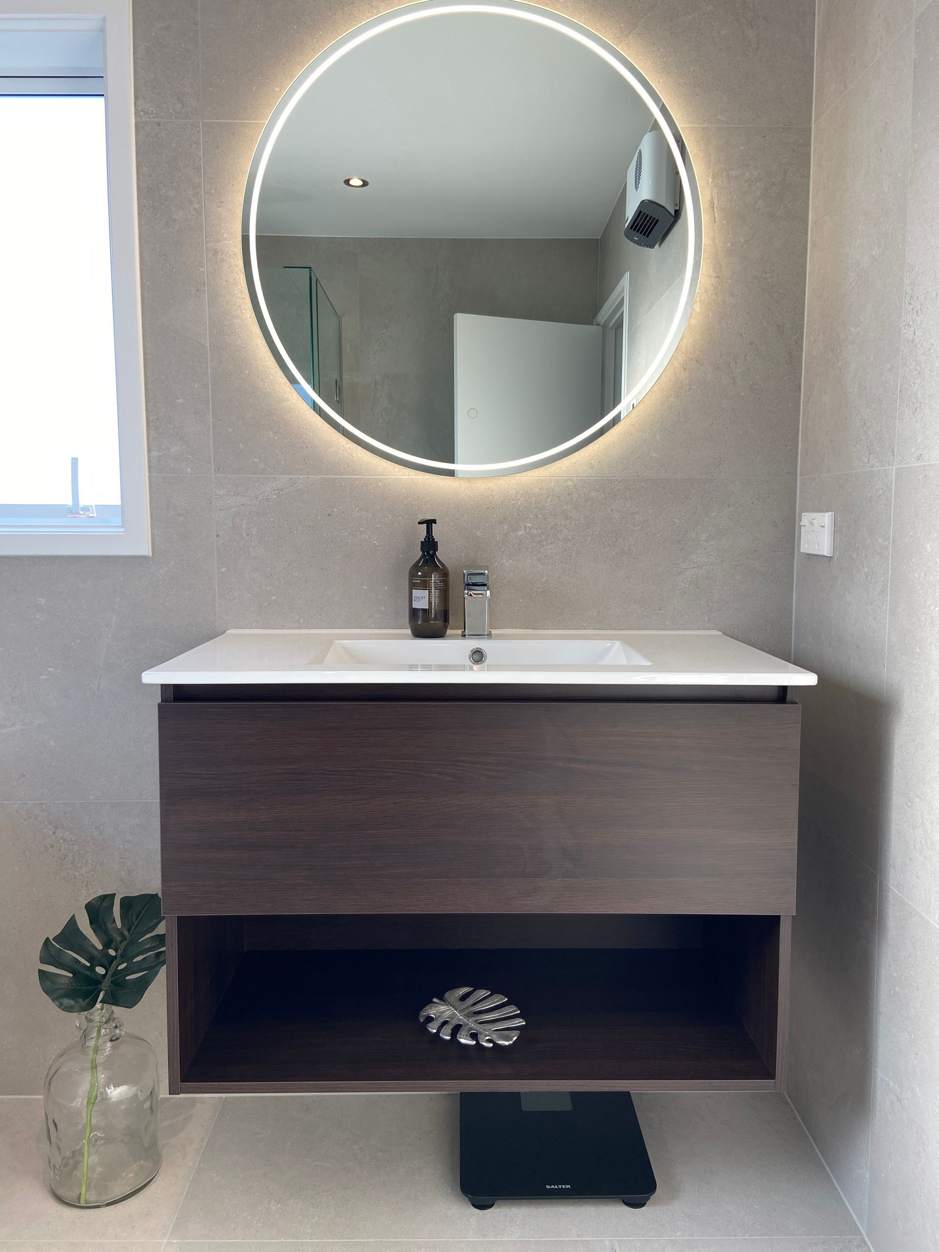 A bathroom with a sink and a round mirror