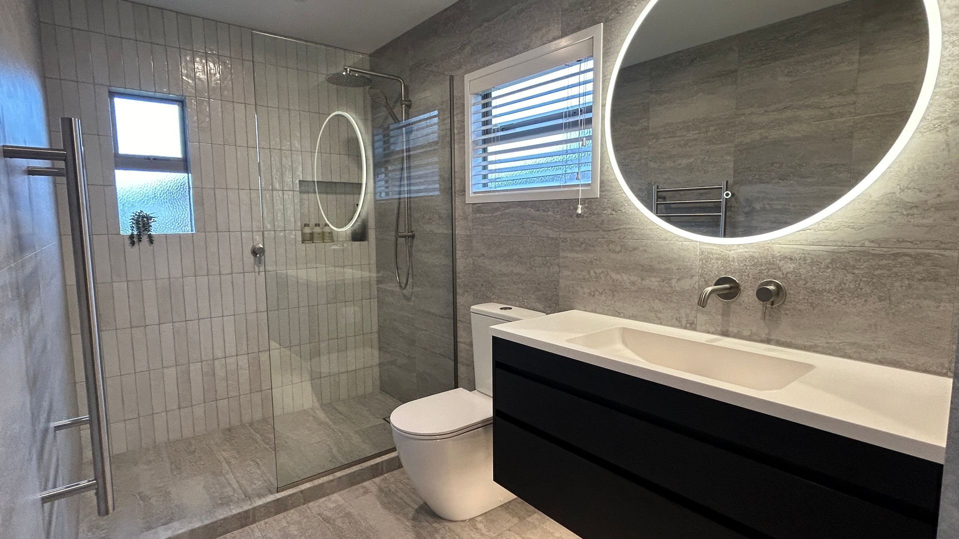 A bathroom with a toilet , sink , shower and mirror.