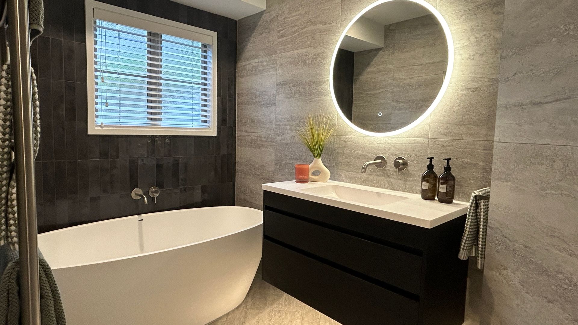 A bathroom with a bathtub , sink , mirror and window.