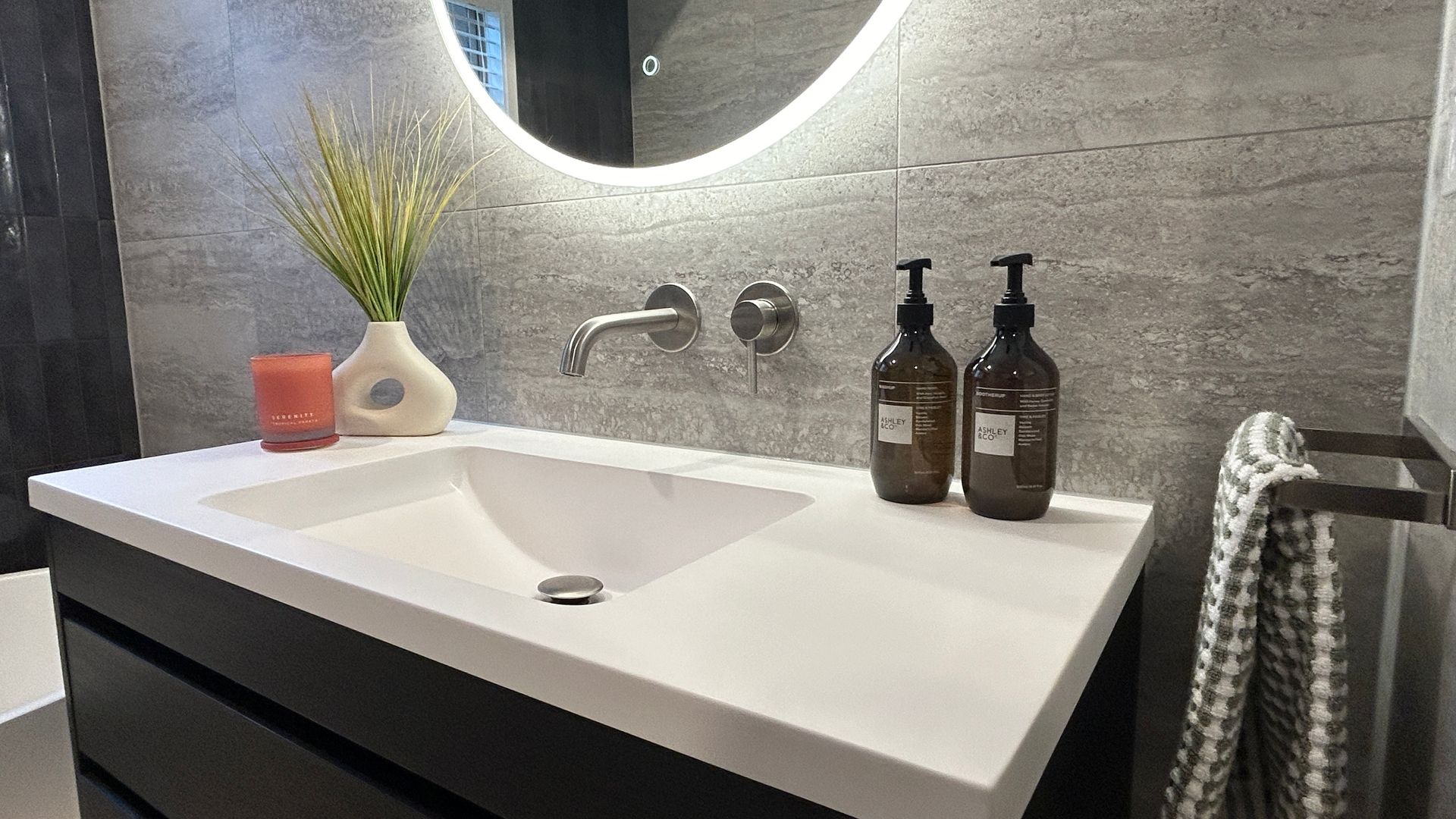 A bathroom sink with two bottles of soap and a mirror.