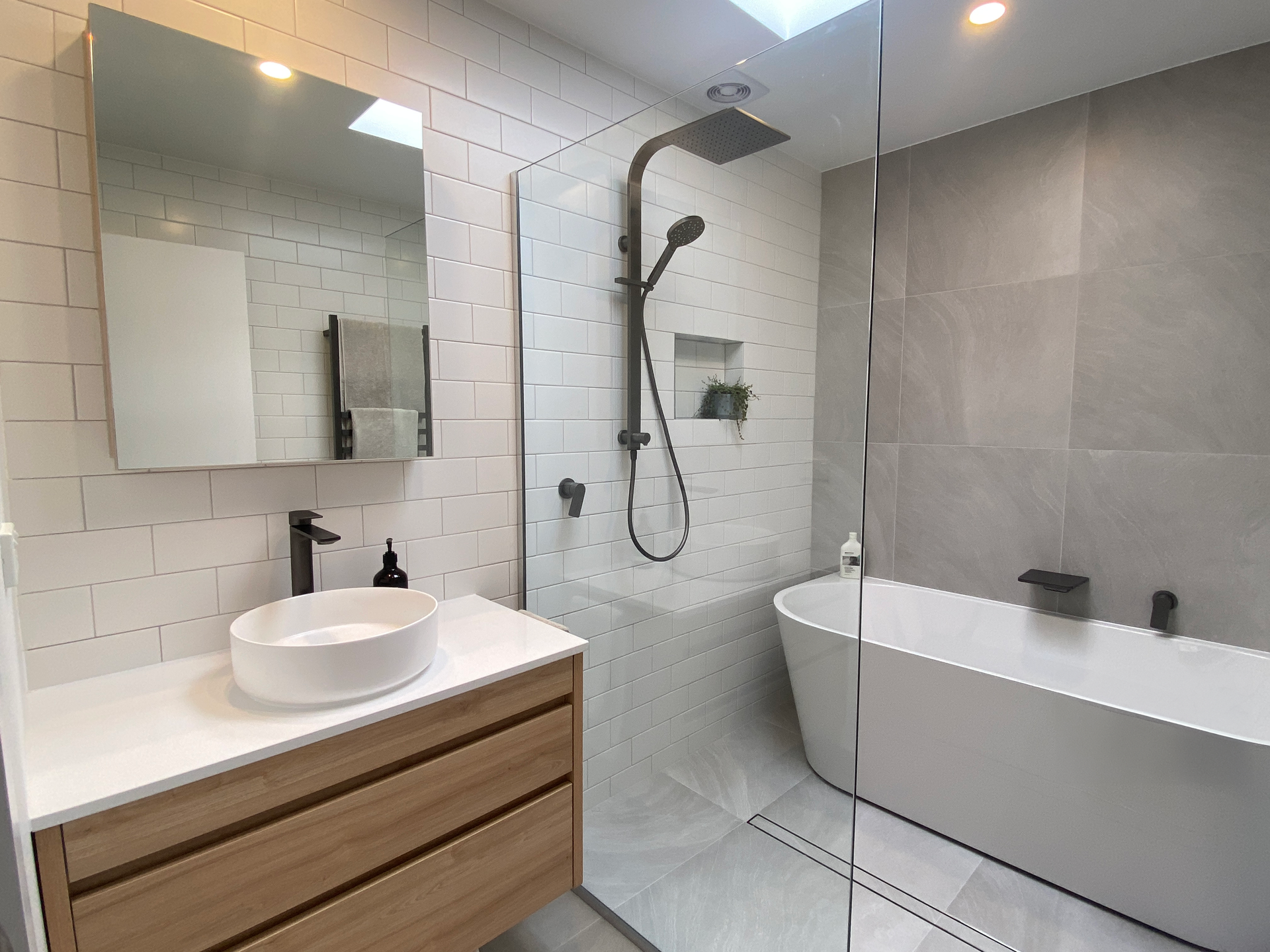 A bathroom with a sink , bathtub , shower and mirror.