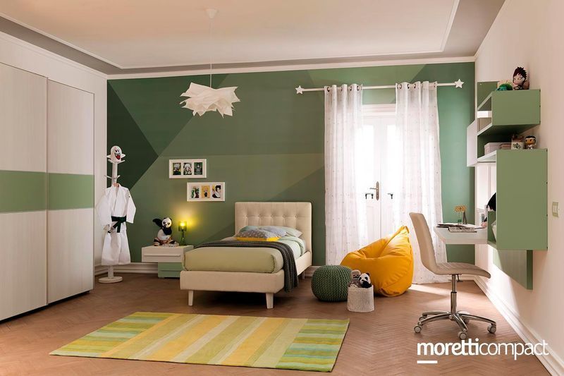 Camera da letto verde con letto, sedia, scrivania, tende e tappeto a righe; arredamento moderno e luminoso.