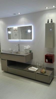 Mobile bagno moderno con specchio a parete, lavabo, armadietti e mensole integrate.