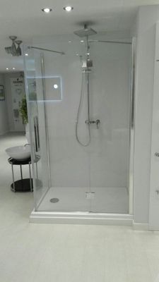 Bagno moderno con box doccia in vetro, pavimento in piastrelle bianche e rubinetteria cromata.