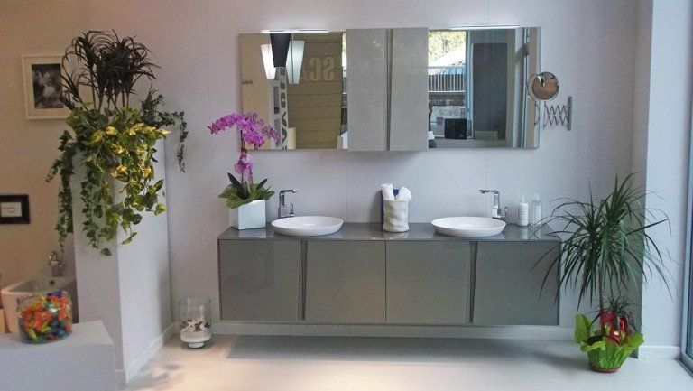 Bagno moderno con mobile lavabo sospeso, armadietti a specchio, piante in vaso e orchidee.