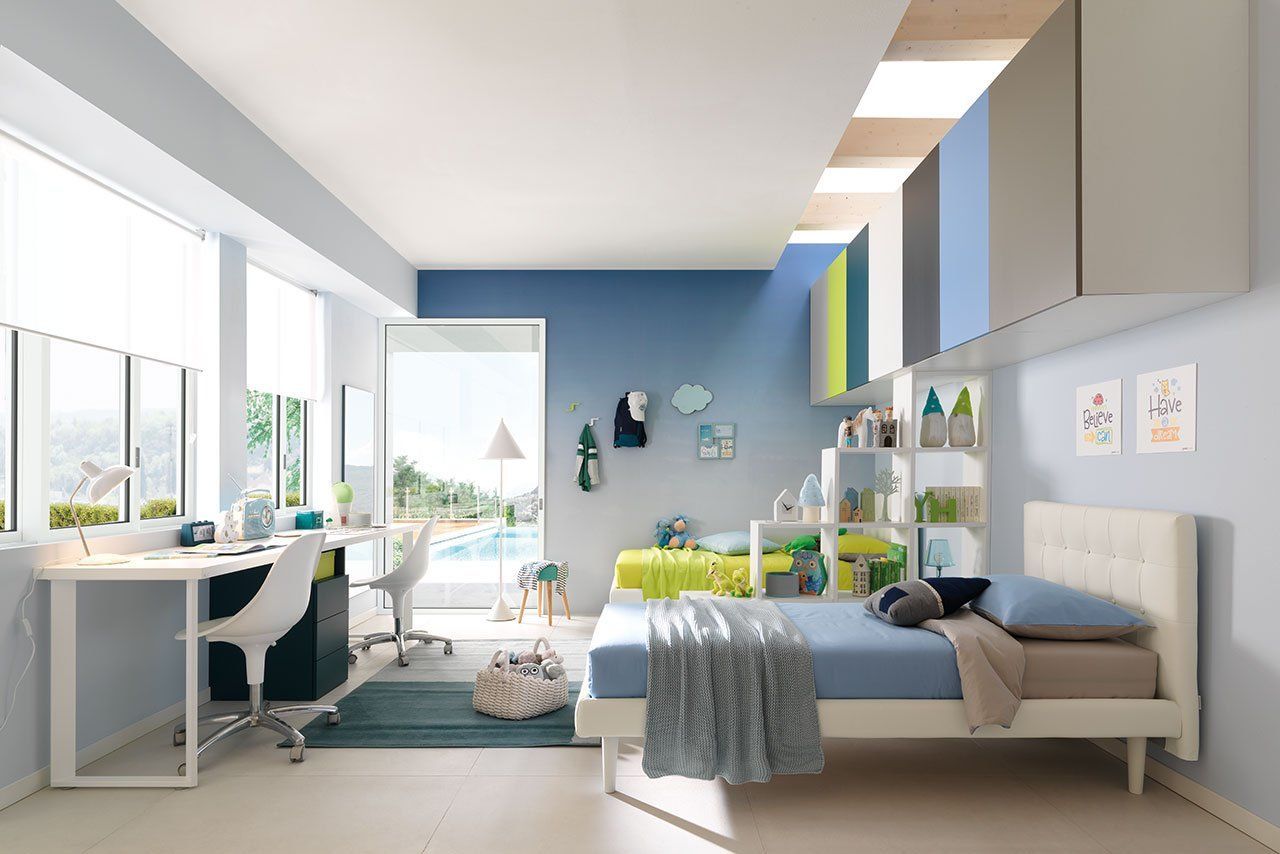 Luminosa camera da letto moderna con due letti singoli, scrivania, parete decorativa blu.