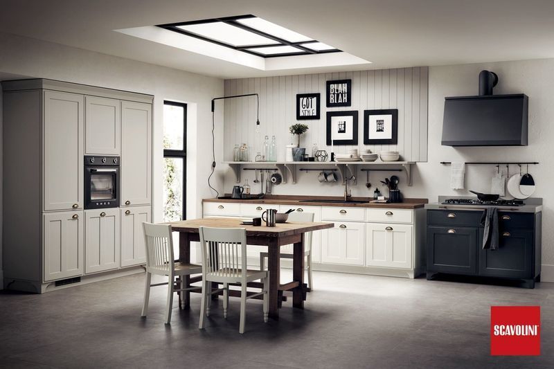 Cucina moderna bianca con isola, tavolo da pranzo, pensili, forno, lavello e TV a parete.