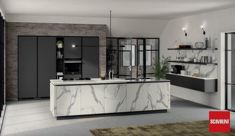 Cucina moderna con isola in marmo, mobili scuri, dispensa in vetro e mensole chiare su pareti grigie.