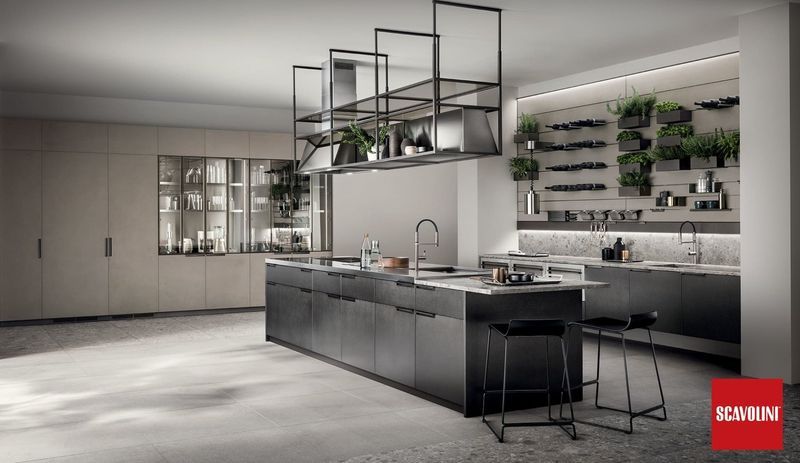 Cucina moderna grigia con isola, lampade a sospensione, mensole a muro per piante e mobili minimalisti.