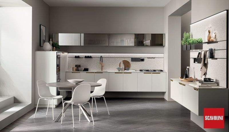 Cucina e zona pranzo moderne e minimaliste con mobili bianchi, pareti grigie e un tavolino con sedie.