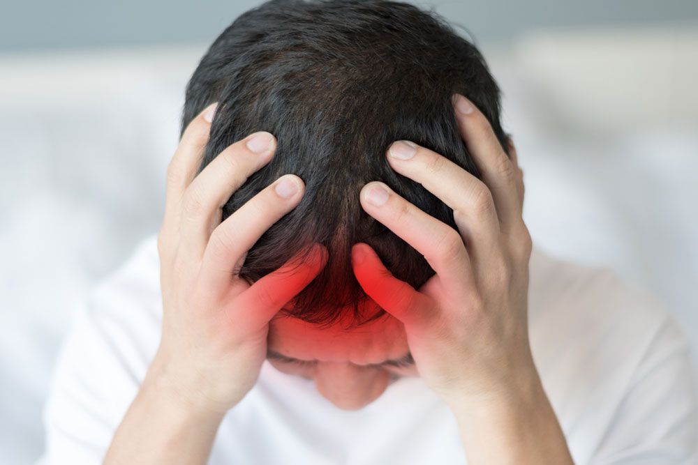 Man clutching his head in pain with the head area highlighted red to depict meningitis