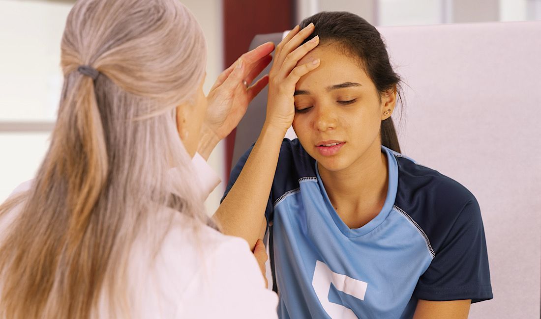Female holding her head and being examined by a doctor for a concussion.