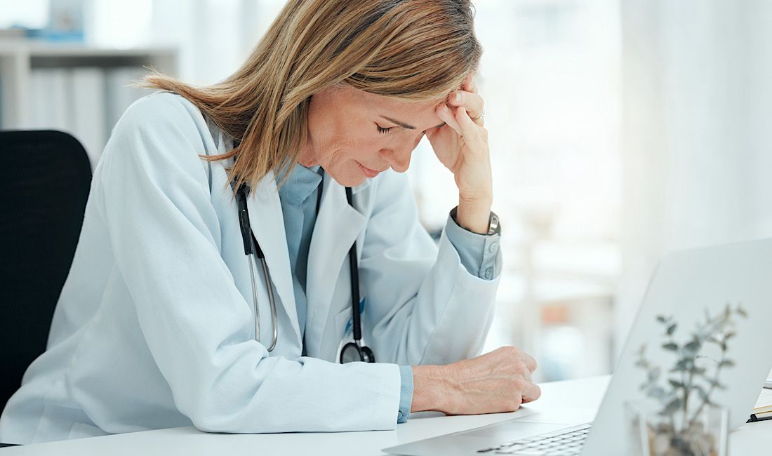Female doctor showing discouragement while sitting at desk looking at results on her computer.