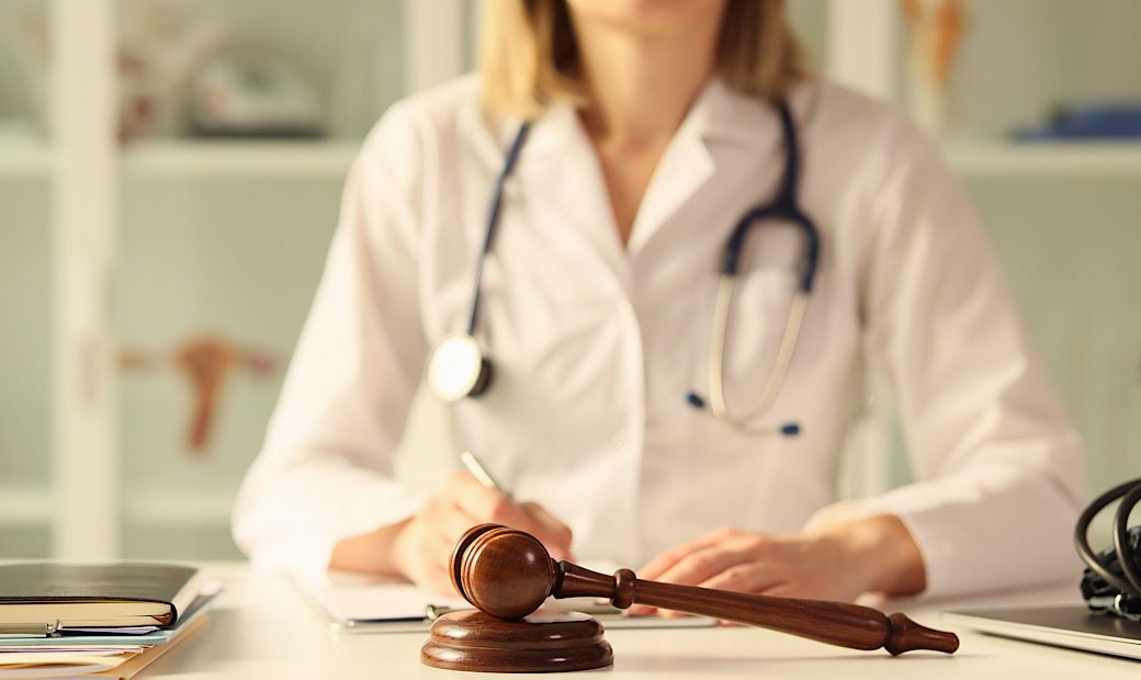 female doctor signing paperwork next to judges gavel